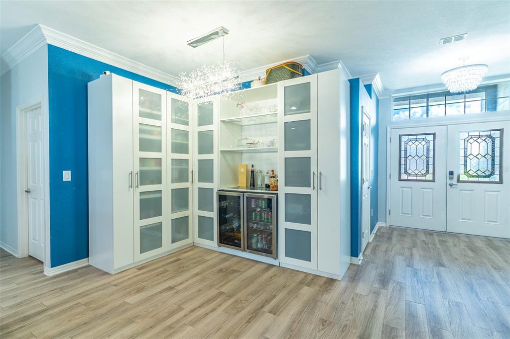 A bright entryway features white cabinetry with glass-paneled doors, a built-in wine cooler, and blue walls — 3749 FIELDSTONE CIRCLE, WINTER HAVEN, FL