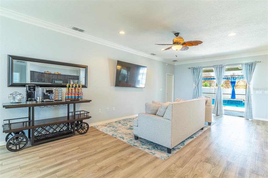 A living room features a coffee bar, a wall-mounted television, and a view of a pool — 3749 FIELDSTONE CIRCLE, WINTER HAVEN, FL