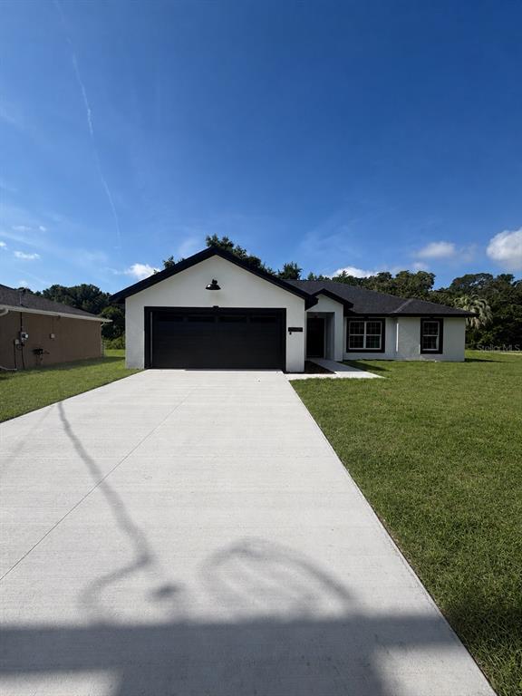 A single-story house with a white exterior, black trim, and a concrete driveway — 2860 SE 146TH PLACE, SUMMERFIELD, FL
