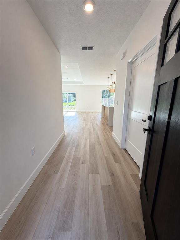 A view from an entryway looking down a hallway toward an open-concept living area — 2860 SE 146TH PLACE, SUMMERFIELD, FL