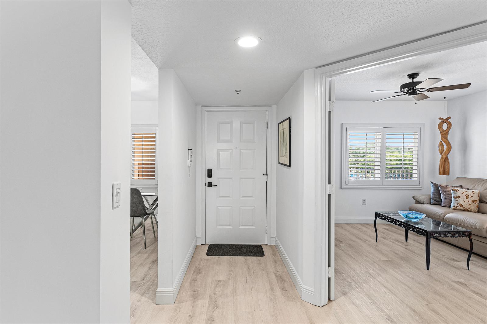 A white front door opens into a hallway with light wood-look flooring and white walls — 5874 Crystal Shores Drive # 304, Boynton Beach FL 33437, BOYNTON BEACH, FL