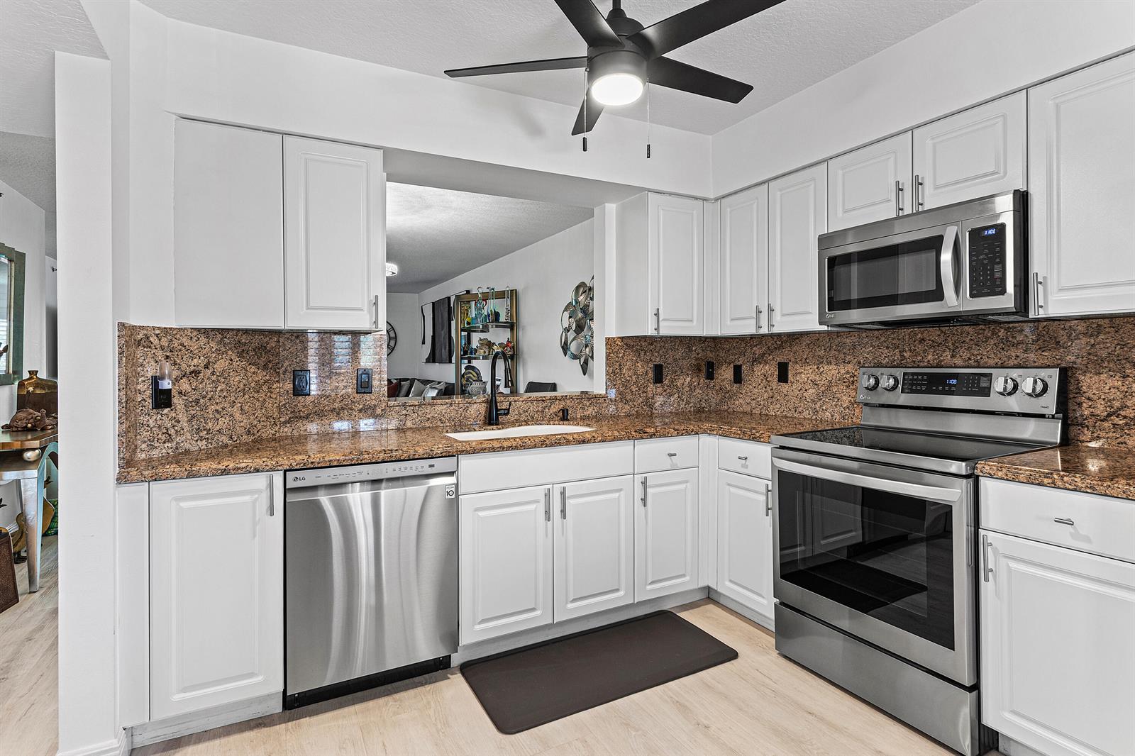 A kitchen features white cabinets, stainless steel appliances, and brown granite countertops — 5874 Crystal Shores Drive # 304, Boynton Beach FL 33437, BOYNTON BEACH, FL
