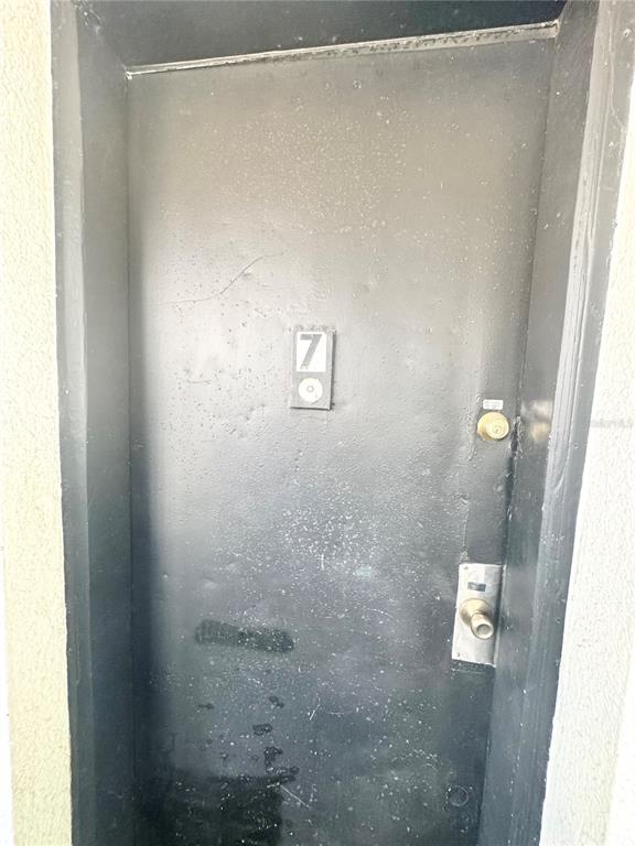 A dark-colored exterior door labeled with the number seven features a metal handle and lock — 704 CORDOVA DRIVE UNIT 7, ORLANDO, FL