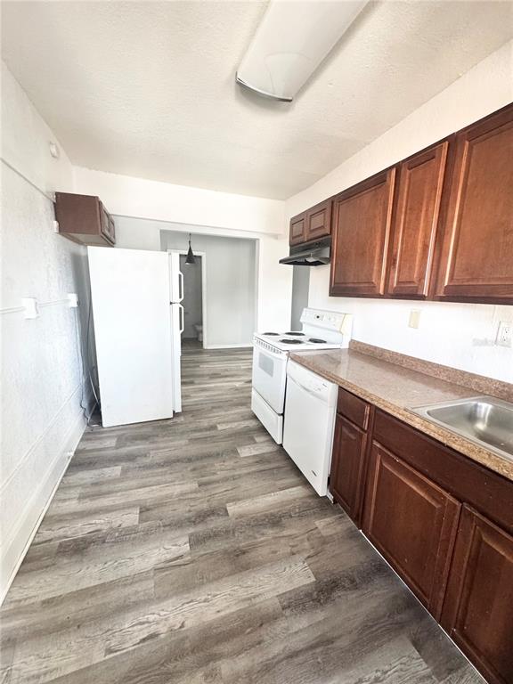 A kitchen features wood cabinets, white appliances, and gray wood-look flooring — 704 CORDOVA DRIVE UNIT 7, ORLANDO, FL