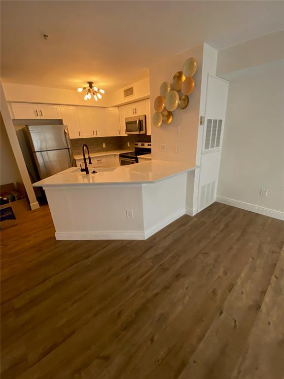 A kitchen with white cabinets, stainless steel appliances, and a peninsula counter on wood flooring — 823 CAMARGO WAY UNIT 105, ALTAMONTE SPRINGS, FL