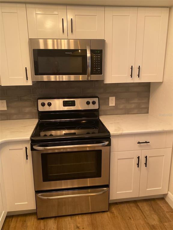 A kitchen features white cabinets, stainless steel appliances, and a gray subway tile backsplash — 823 CAMARGO WAY UNIT 105, ALTAMONTE SPRINGS, FL