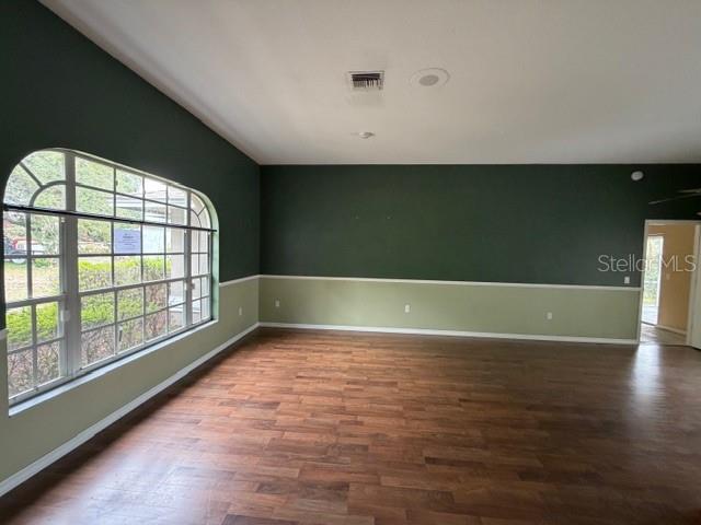 A living room features dark green and light green walls, wood-look flooring, and arched windows — 1235 ODONIEL LOOP S, LAKELAND, FL