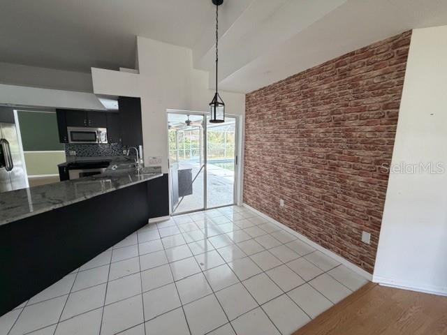 A dining area features white tile floors, a brick-patterned accent wall, and sliding glass doors — 1235 ODONIEL LOOP S, LAKELAND, FL