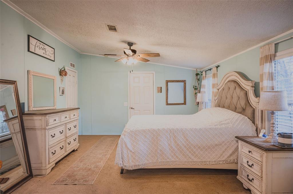 A bedroom features light blue walls, a tufted headboard, white furniture, and a ceiling fan — 7296 NW 170TH STREET, TRENTON, FL