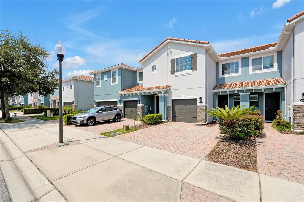 A two-story townhouse with a paved driveway, a garage, and a light-colored stucco exterior — 342 REED GRASS DRIVE, OVIEDO, FL