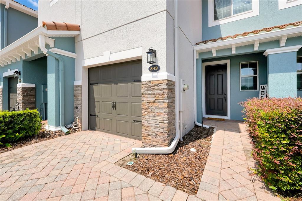 A residential exterior features a garage, a front door, and a paved walkway with landscaping — 342 REED GRASS DRIVE, OVIEDO, FL