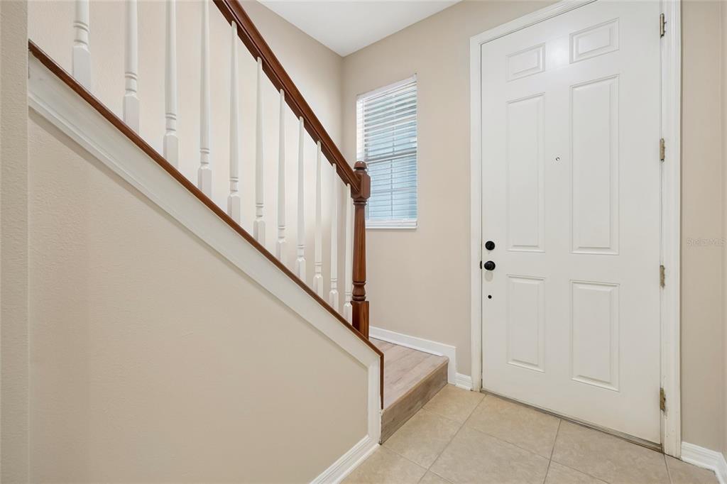 An entryway features a white front door, a staircase with a wooden handrail, and tile flooring — 342 REED GRASS DRIVE, OVIEDO, FL