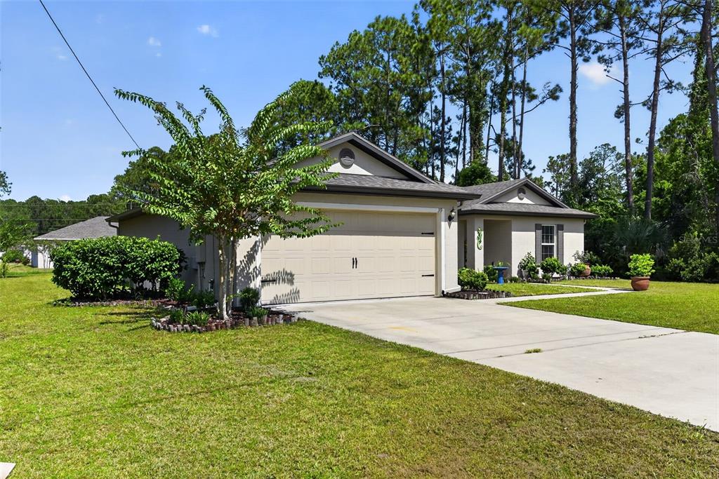 A single-story house with a beige exterior, a two-car garage, and a concrete driveway — 39 SEDERHOLM PATH, PALM COAST, FL