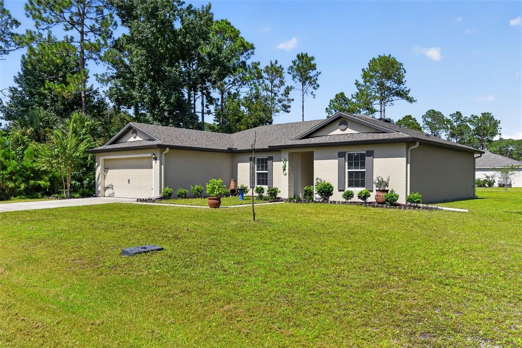 A single-story house with a beige stucco exterior, a two-car garage, and a grassy yard — 39 SEDERHOLM PATH, PALM COAST, FL