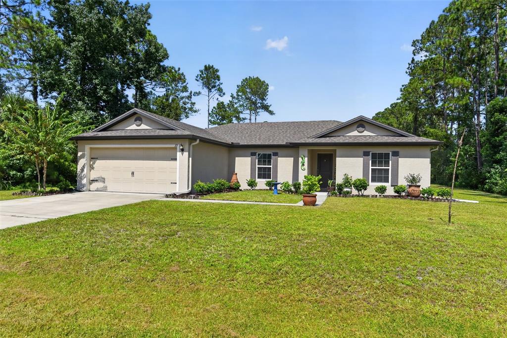 A single-story house with a beige stucco exterior, a two-car garage, and a grassy lawn — 39 SEDERHOLM PATH, PALM COAST, FL