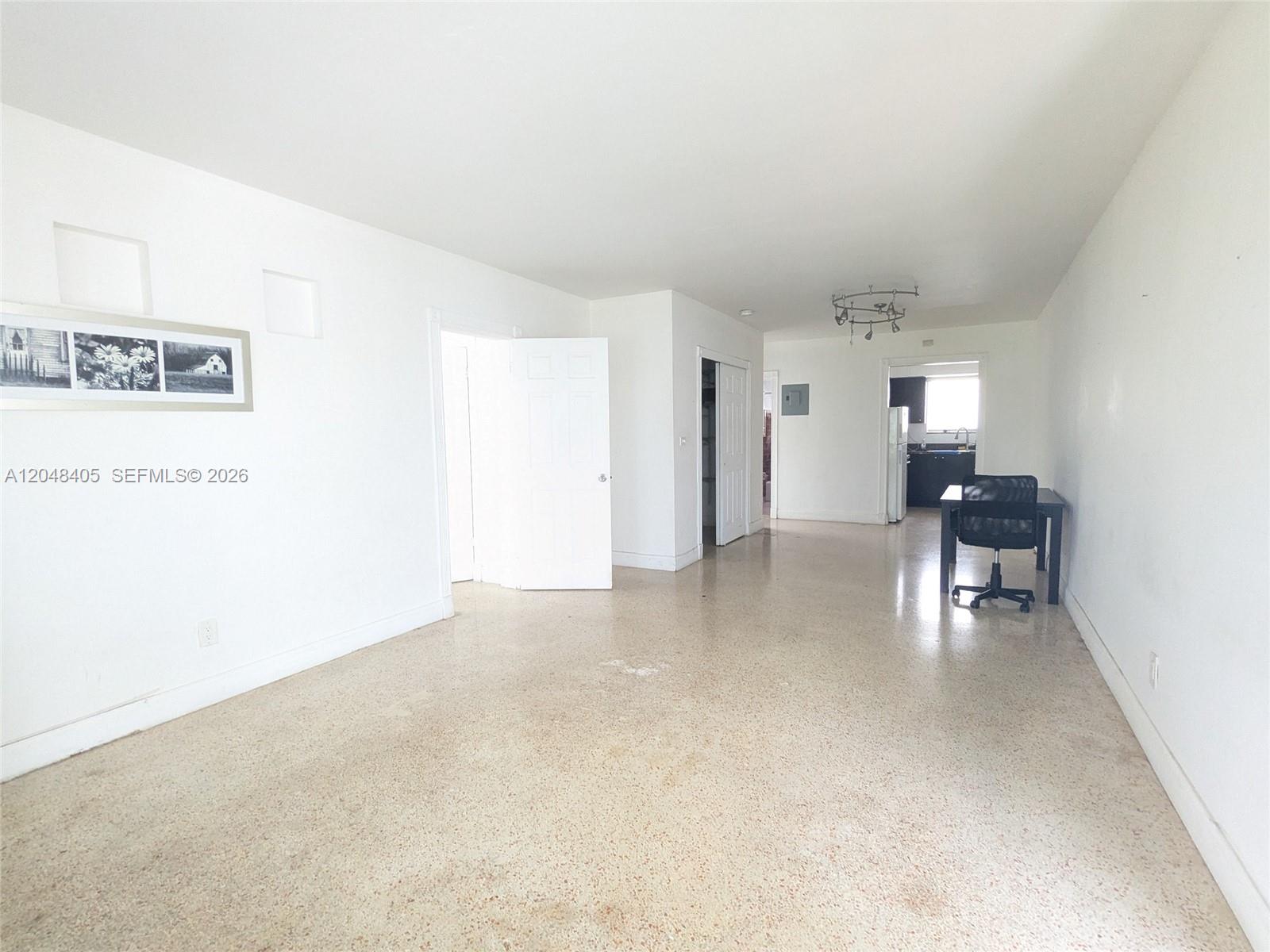 A bright, open-plan room features white walls, terrazzo flooring, and a small kitchen area — 7805 Crespi Blvd # 1, Miami Beach FL 33141, MIAMI BEACH, FL