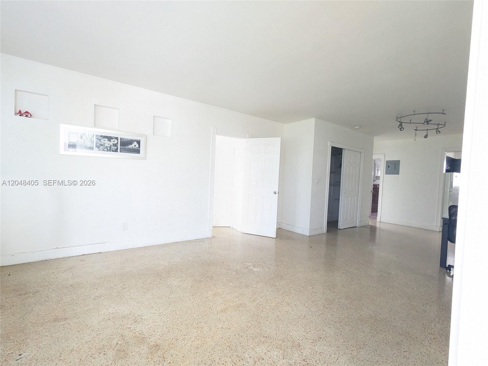 A bright, empty room features white walls, a light-colored terrazzo floor, and multiple doorways — 7805 Crespi Blvd # 1, Miami Beach FL 33141, MIAMI BEACH, FL
