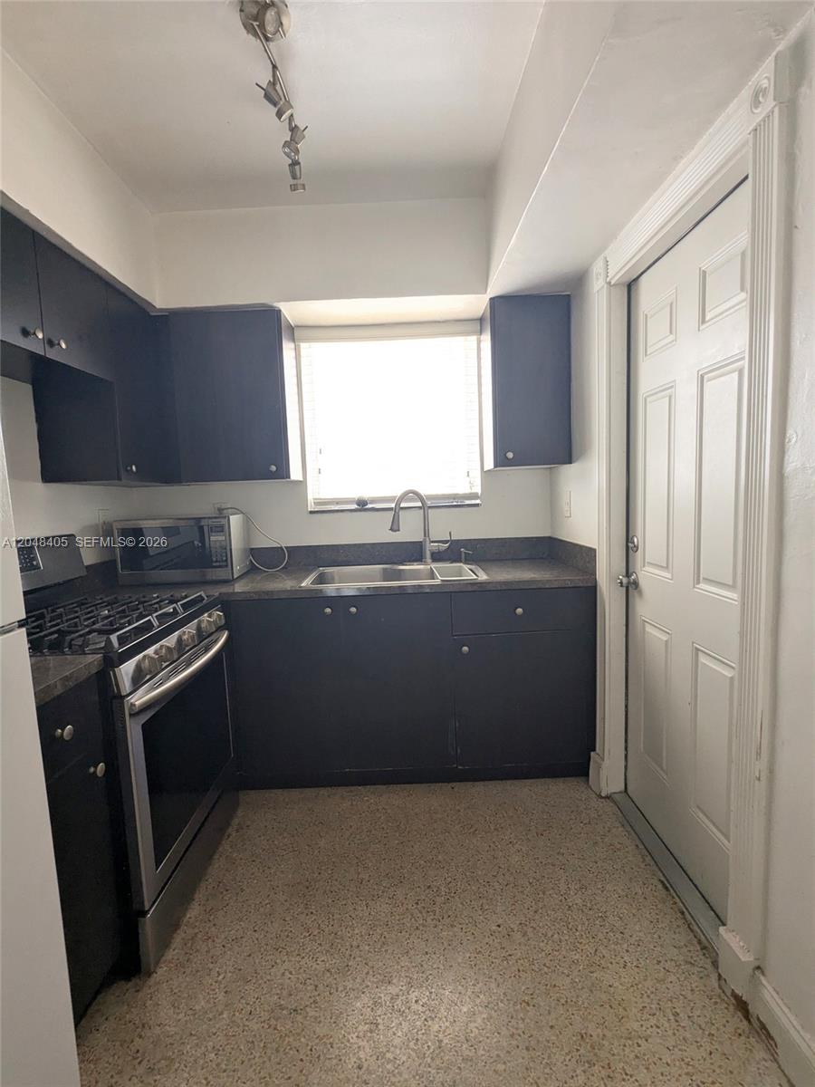 A kitchen features dark cabinets, stainless steel appliances, a window above the sink, and terrazzo flooring — 7805 Crespi Blvd # 1, Miami Beach FL 33141, MIAMI BEACH, FL