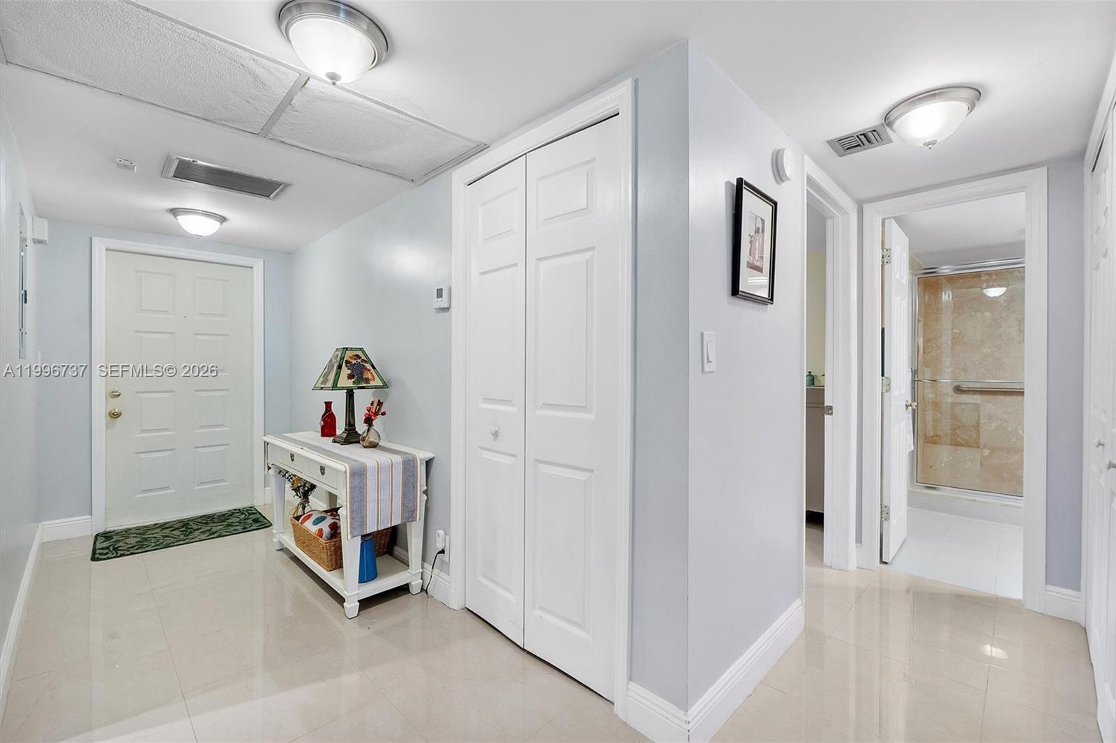 A bright entryway features light tile floors, a white console table, and two closed doors — 3503 Oaks Way # 308, Pompano Beach FL 33069, POMPANO BEACH, FL