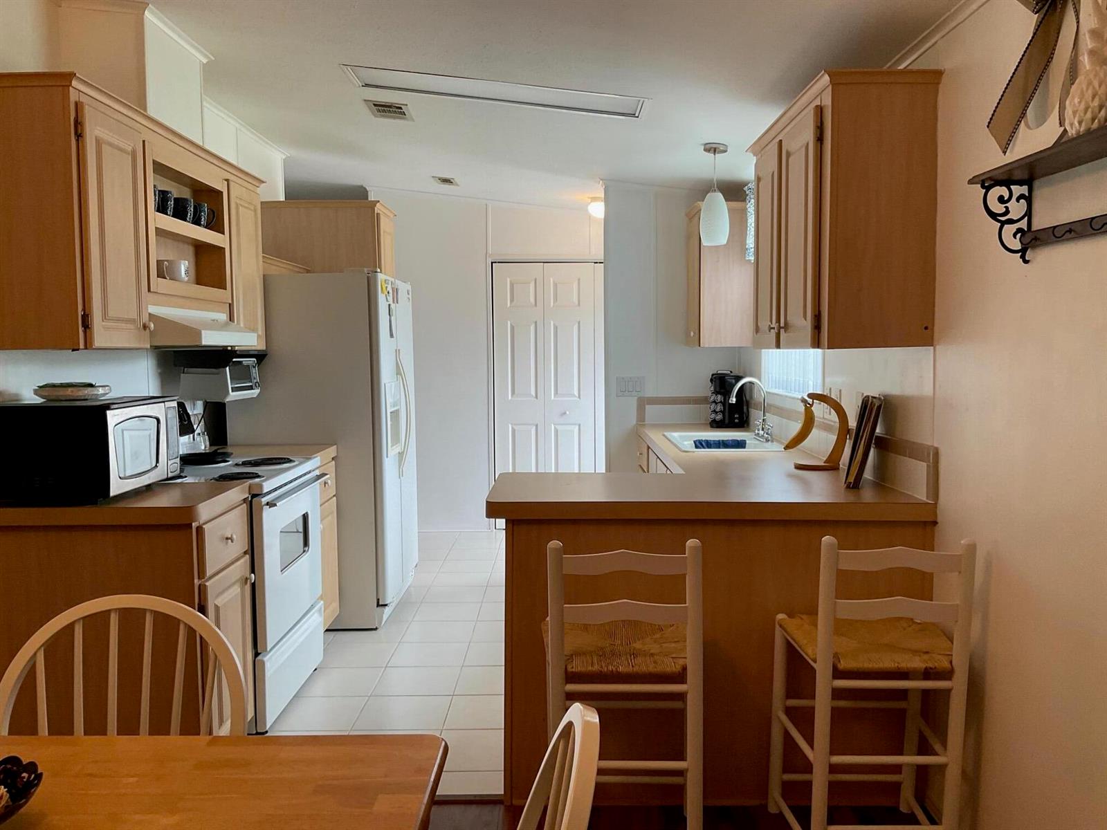 A kitchen with light wood cabinets, white appliances, a breakfast bar, and tile flooring — 2518 SE 32nd Street, Okeechobee FL 34974, OKEECHOBEE, FL