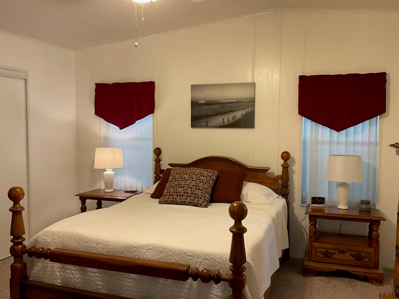 A bedroom features a wooden four-poster bed, two nightstands with lamps, and red window valances — 2518 SE 32nd Street, Okeechobee FL 34974, OKEECHOBEE, FL