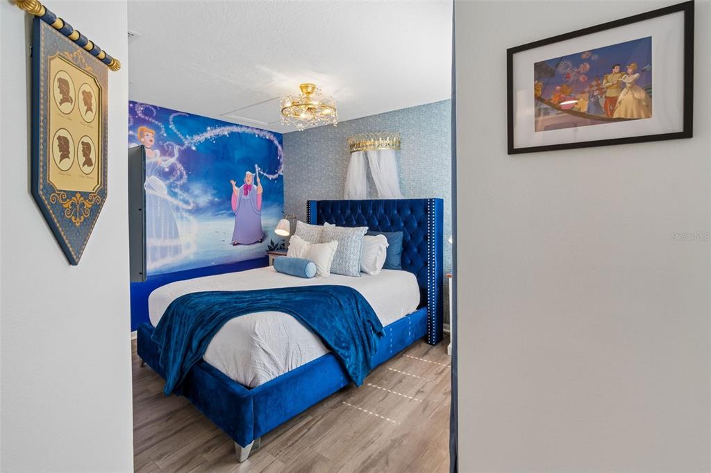 A bedroom features a blue tufted bed, Cinderella-themed wall mural, and a framed wall print — 668 CARIBBEAN DRIVE, DAVENPORT, FL