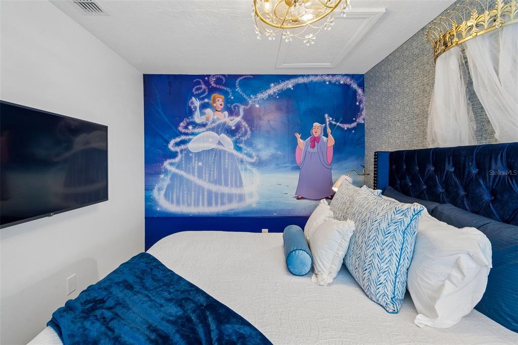 A bedroom features a Cinderella-themed mural, a blue tufted headboard, and a canopy bed — 668 CARIBBEAN DRIVE, DAVENPORT, FL