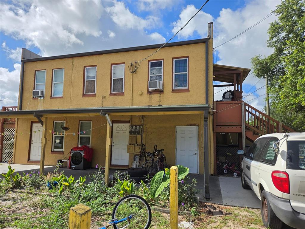 A two-story yellow stucco building features multiple doors, windows, and an exterior wooden staircase — 1725 OLD BARTOW ROAD, LAKE WALES, FL