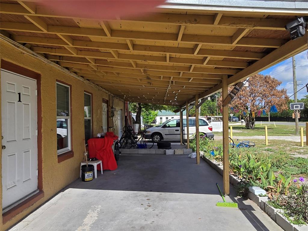 A covered concrete carport extends from the side of a yellow stucco building — 1725 OLD BARTOW ROAD, LAKE WALES, FL