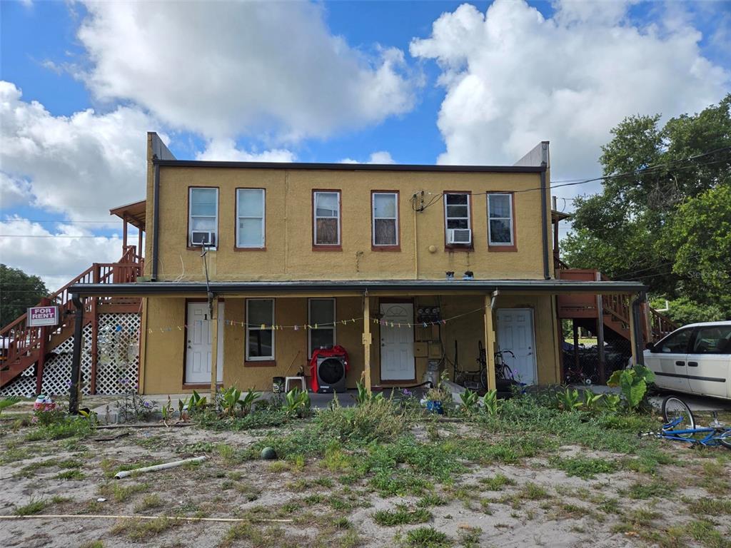 A two-story yellow stucco building with a covered porch and exterior wooden stairs — 1725 OLD BARTOW ROAD, LAKE WALES, FL