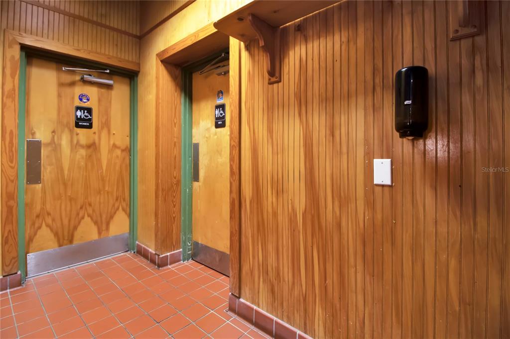 A hallway with wood-paneled walls, tiled floors, and two doors leading to restrooms — 1152 TAMIAMI TRAIL, PORT CHARLOTTE, FL