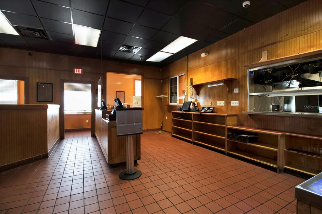 An empty commercial space features wood-paneled walls, a tiled floor, and a service counter — 1152 TAMIAMI TRAIL, PORT CHARLOTTE, FL