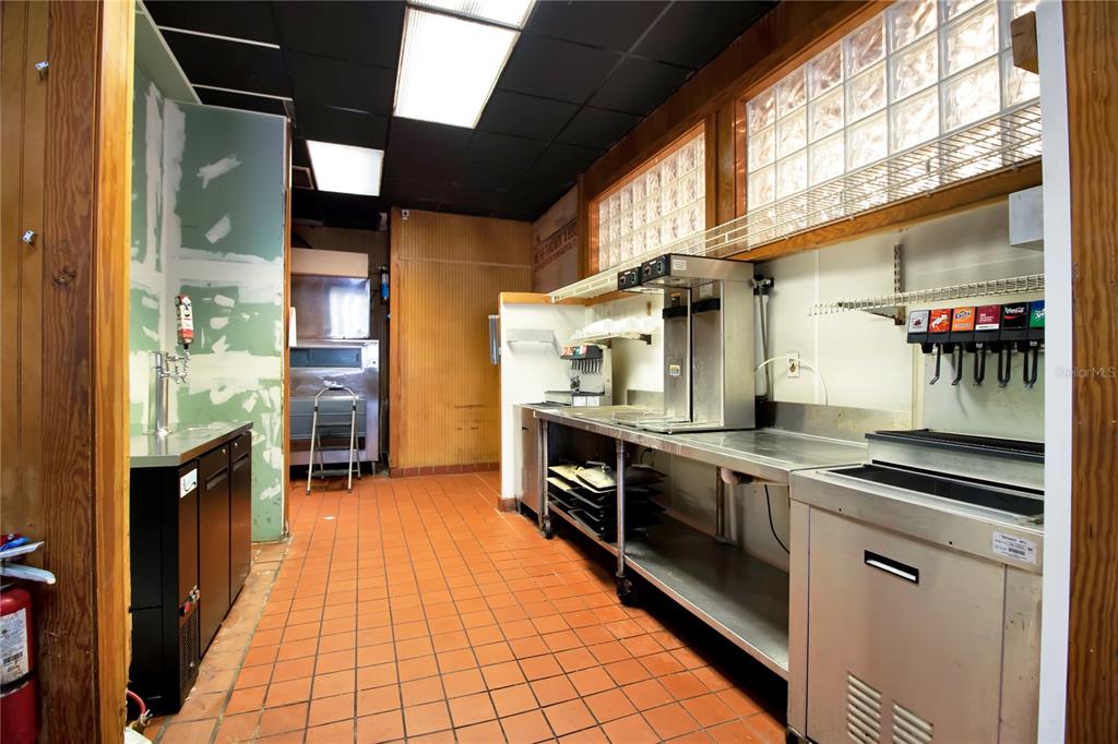 A commercial kitchen features stainless steel prep tables, a soda fountain, and orange tile flooring — 1152 TAMIAMI TRAIL, PORT CHARLOTTE, FL