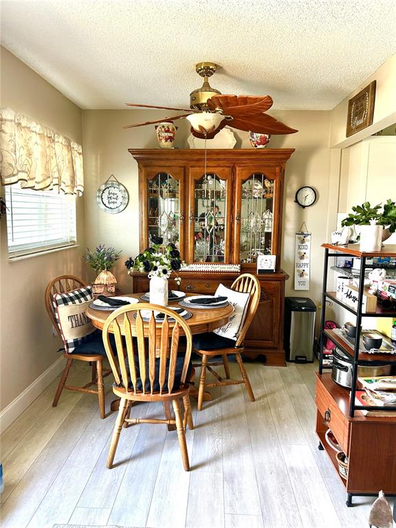 A dining room features a wooden hutch, a round table with chairs, and a ceiling fan — 11909 BAYONET LANE UNIT 113A, NEW PORT RICHEY, FL