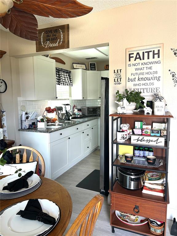 A kitchen with white cabinets, granite countertops, and a wooden shelving unit in the foreground — 11909 BAYONET LANE UNIT 113A, NEW PORT RICHEY, FL
