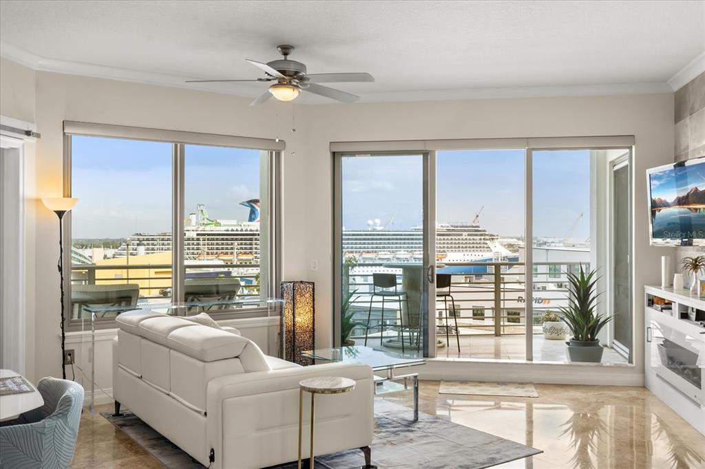 A living room with a white sofa, marble floors, and a balcony overlooking cruise ships — 1209 E CUMBERLAND AVENUE UNIT 807, TAMPA, FL