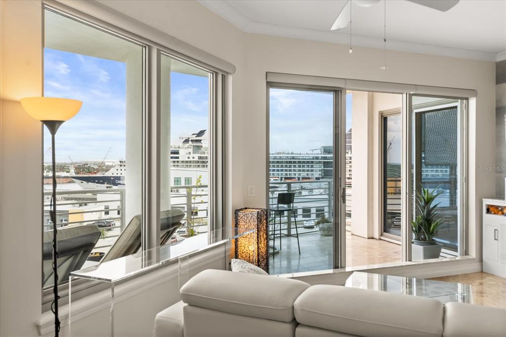A living room with a white sofa, glass tables, and a balcony overlooking a cruise ship — 1209 E CUMBERLAND AVENUE UNIT 807, TAMPA, FL