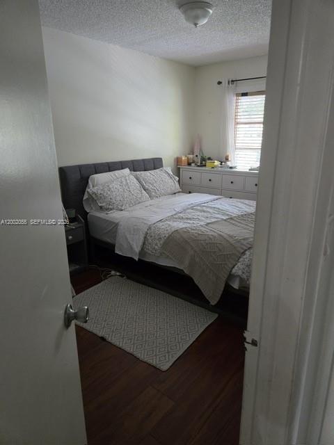 A bedroom features a gray upholstered bed, a white dresser, and wood-look flooring — HOLLYWOOD, FL