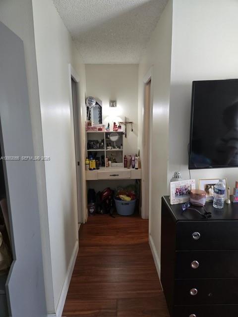 A hallway with wood-look flooring leads to a built-in vanity area with shelving — HOLLYWOOD, FL