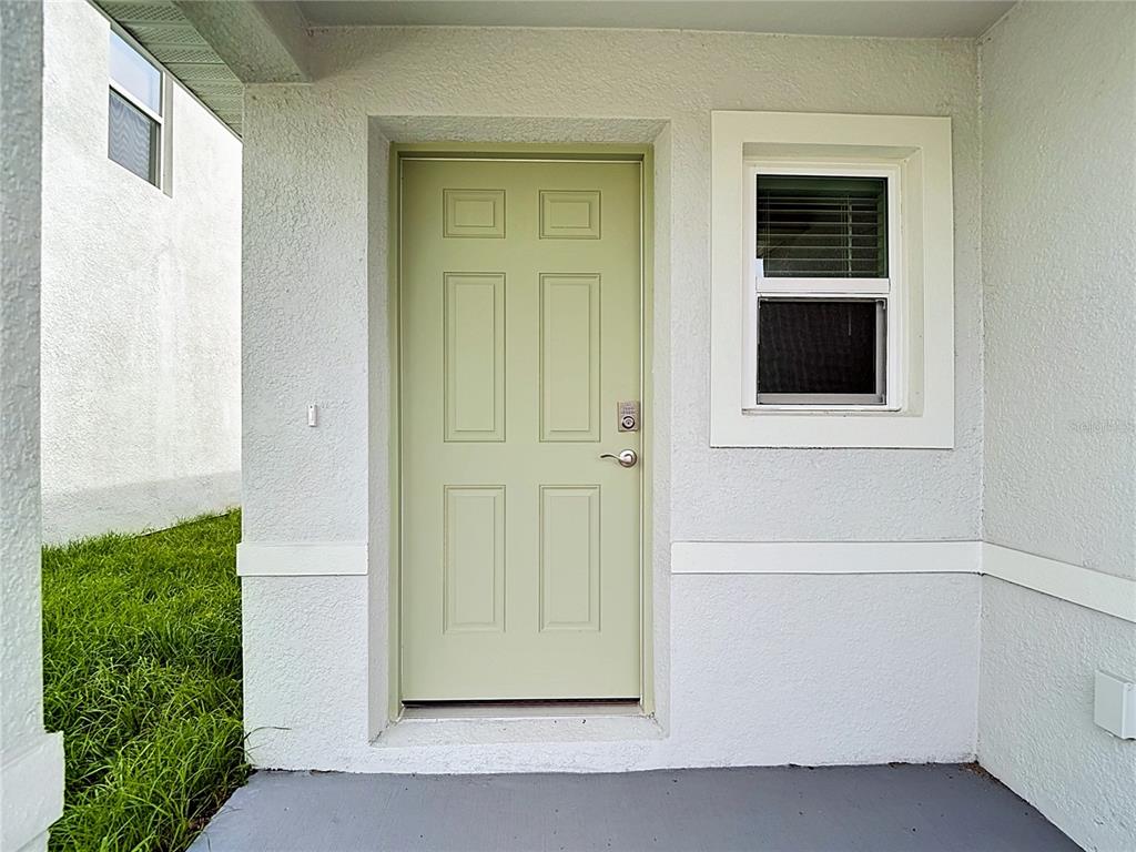 A light green front door with a window and a small porch area — 31115 SILVER STAGE DRIVE, BROOKSVILLE, FL