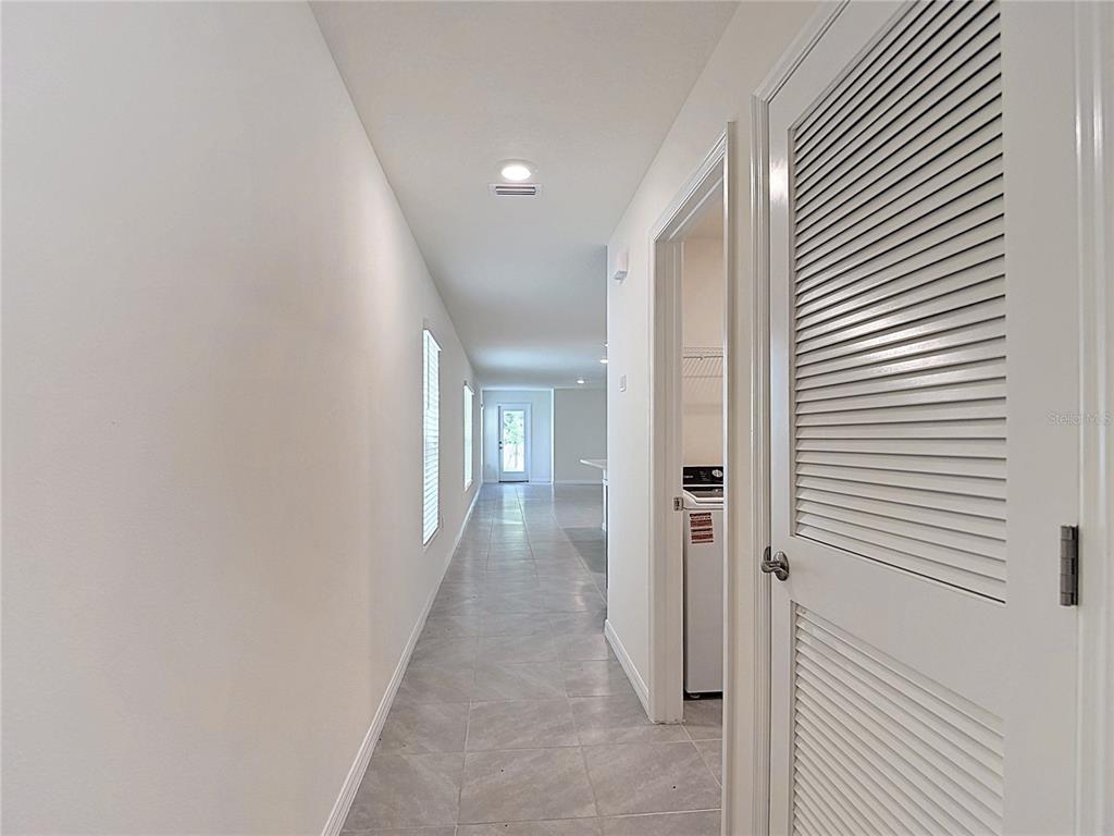 A hallway with tile flooring leads toward a doorway with a view of the outdoors — 31115 SILVER STAGE DRIVE, BROOKSVILLE, FL