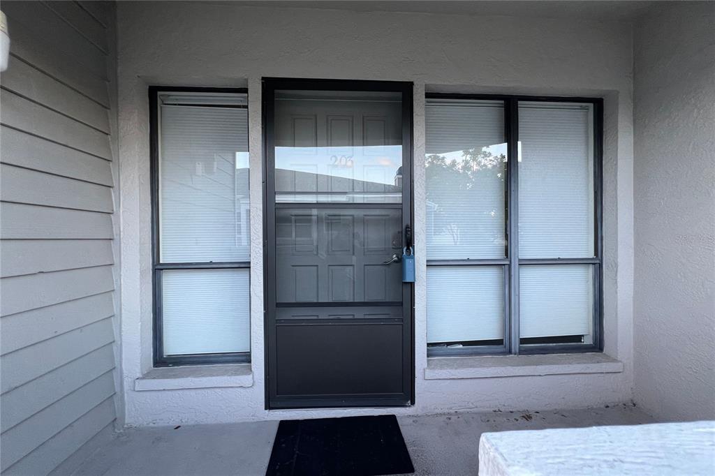 A front entryway features a dark storm door with the number 206 and two windows — 10606 LONGWOOD DRIVE UNIT 203B, SEMINOLE, FL