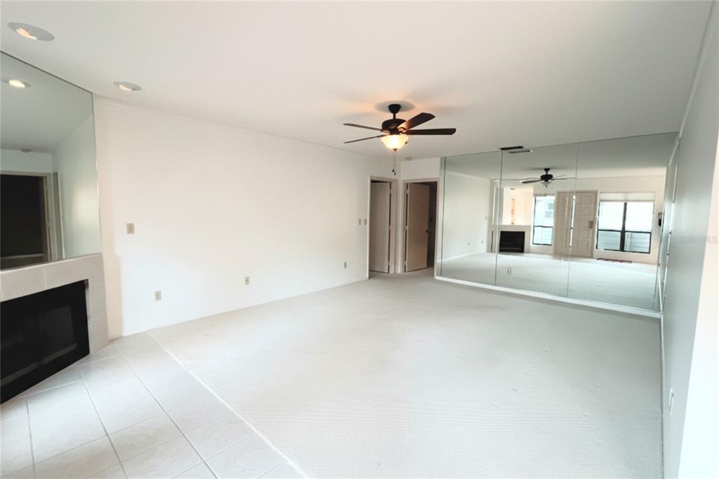 A living room with white carpet, a fireplace, and a large mirrored wall — 10606 LONGWOOD DRIVE UNIT 203B, SEMINOLE, FL