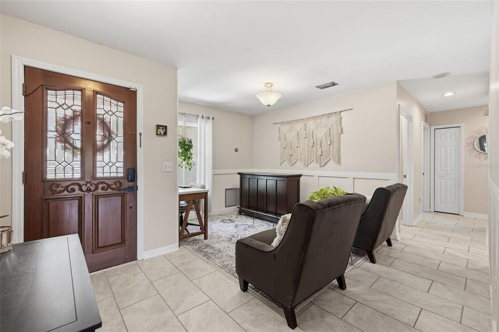 An entryway features a wooden front door, tile flooring, two armchairs, and a console table — 17508 BRANDYWINE DRIVE, LUTZ, FL