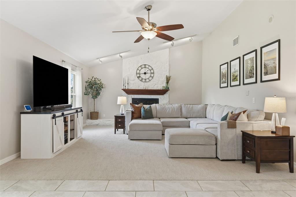 A living room features a large sectional sofa, a white stone fireplace, and a television — 17508 BRANDYWINE DRIVE, LUTZ, FL