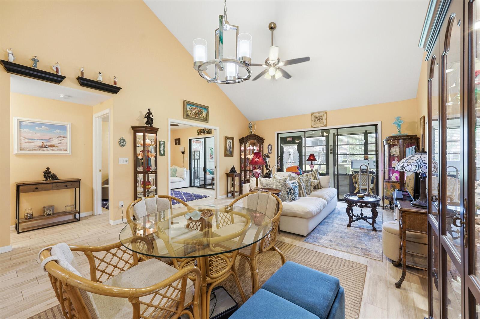 A living and dining area with vaulted ceilings, light-colored tile floors, and rattan furniture — 6167 SE Georgetown Place, Hobe Sound FL 33455, HOBE SOUND, FL