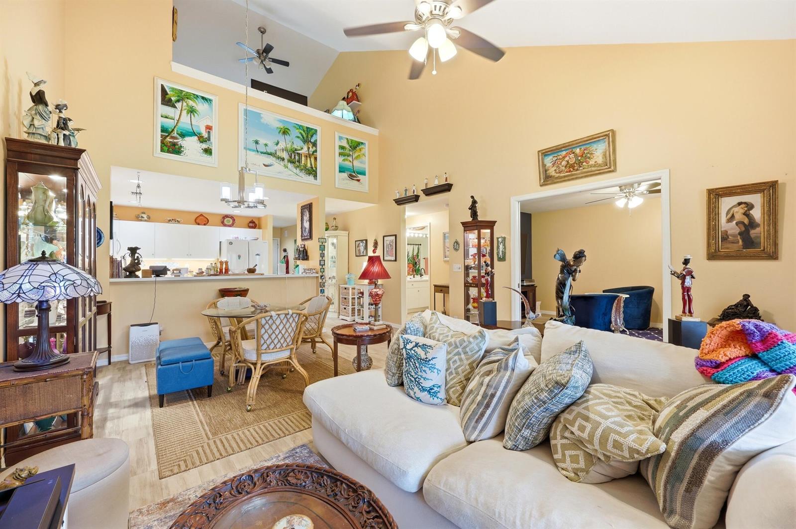 A living room with vaulted ceilings, beige walls, a sectional sofa, and an open kitchen — 6167 SE Georgetown Place, Hobe Sound FL 33455, HOBE SOUND, FL