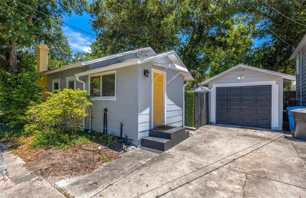 A gray house with a yellow front door and a detached garage sits on a lot — 1162 HIGHLAND STREET N, ST PETERSBURG, FL