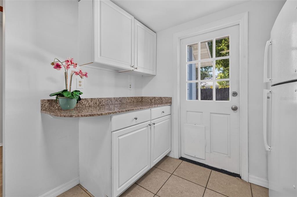 A kitchen area features white cabinets, granite countertops, tile flooring, and a glass-paneled exterior door — 1162 HIGHLAND STREET N, ST PETERSBURG, FL