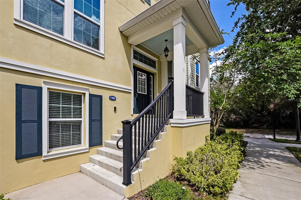 A yellow house exterior features a front porch with stairs and dark blue shutters — 1384 MILL STREAM LANE, WINTER SPRINGS, FL